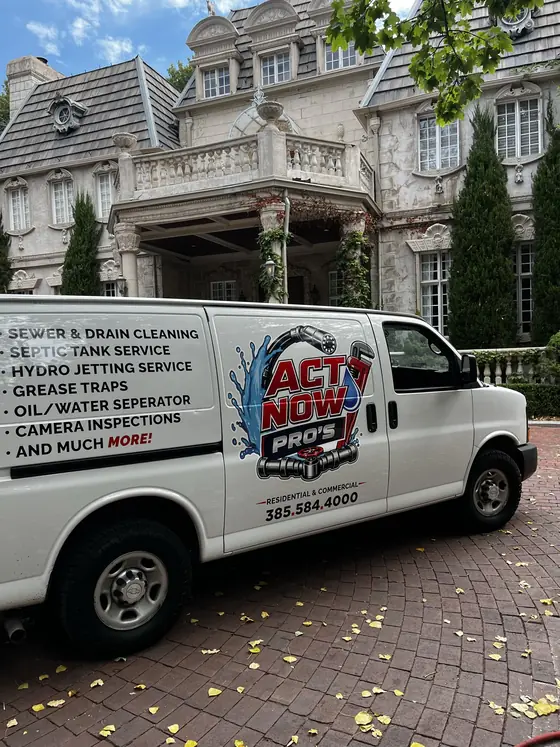 Camioneta de servicio de alcantarillado y drenaje de Act Now Pros frente a una propiedad