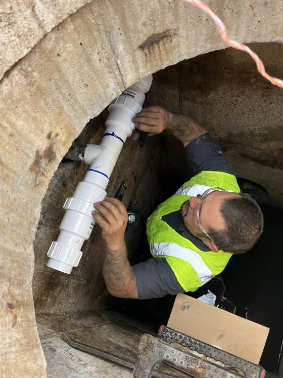 Técnico trabajando a lo largo de un canal de piso abierto en un espacio comercial