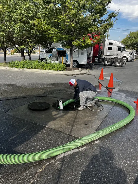 Manguera de bombeo y conos de seguridad alrededor de un punto de acceso de servicio abierto